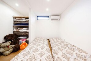 A small room with a bed, a shelf with folded blankets, and an air conditioning unit. - 【Antiques Gifu Station East】Entire Villa for up to 10 Guests 10-Min Walk from JR Gifu Station (Gifu)