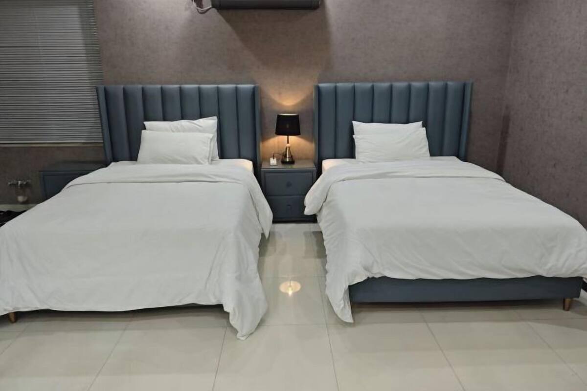 A double bed room with a blue headboard, two bedside tables with lamps, and white bedding.