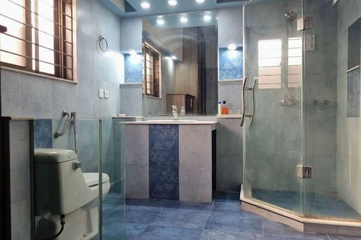 A modern bathroom with a glass shower enclosure, a toilet, and a sink with a mirror above it.