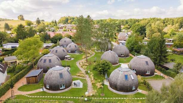 A cluster of dome-shaped buildings surrounded by lush greenery and a hilly landscape. - Vacation home "Kirana" on Lake Tollensesee in Penzlin Wustrow (Penzlin)