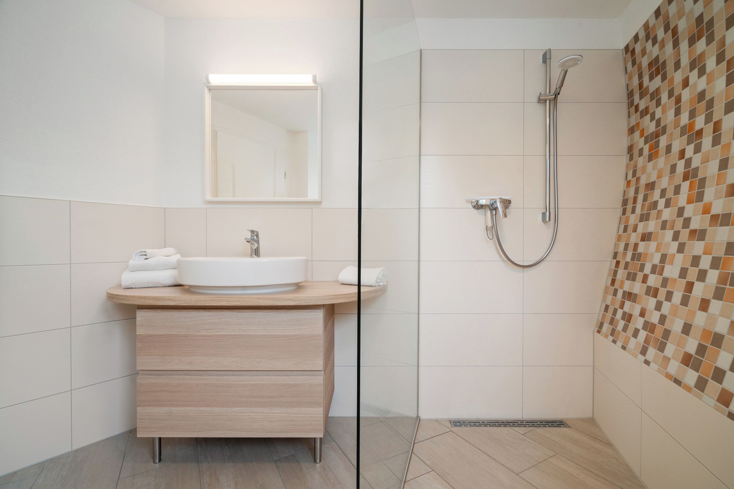 A modern bathroom with a sink, mirror, and shower.