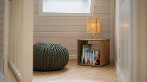 A room with a skylight, a wooden floor, a knitted pouf, and a small bookshelf with books. - Vacation home "Kirana" on Lake Tollensesee in Penzlin Wustrow (Penzlin)