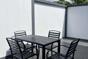 Een terras met een tafel en stoelen, omgeven door witte muren.