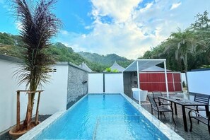 Una piscina con vistas a una montaña, un atizador de madera y una valla roja.