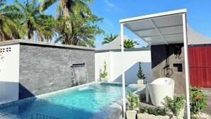 A modern outdoor pool area with a stone wall, a waterfall feature, and a covered seating area with a white tub. - TJ POOL VILLA AONANG KRABI (Krabi)