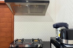 Una cocina con estufa a gas, cafetera y extractor de acero inoxidable.