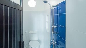A bathroom with a toilet, a shower with a glass enclosure, and a window above the toilet. - Vj Sweethome Syariah Near GOR Turida (Turida)