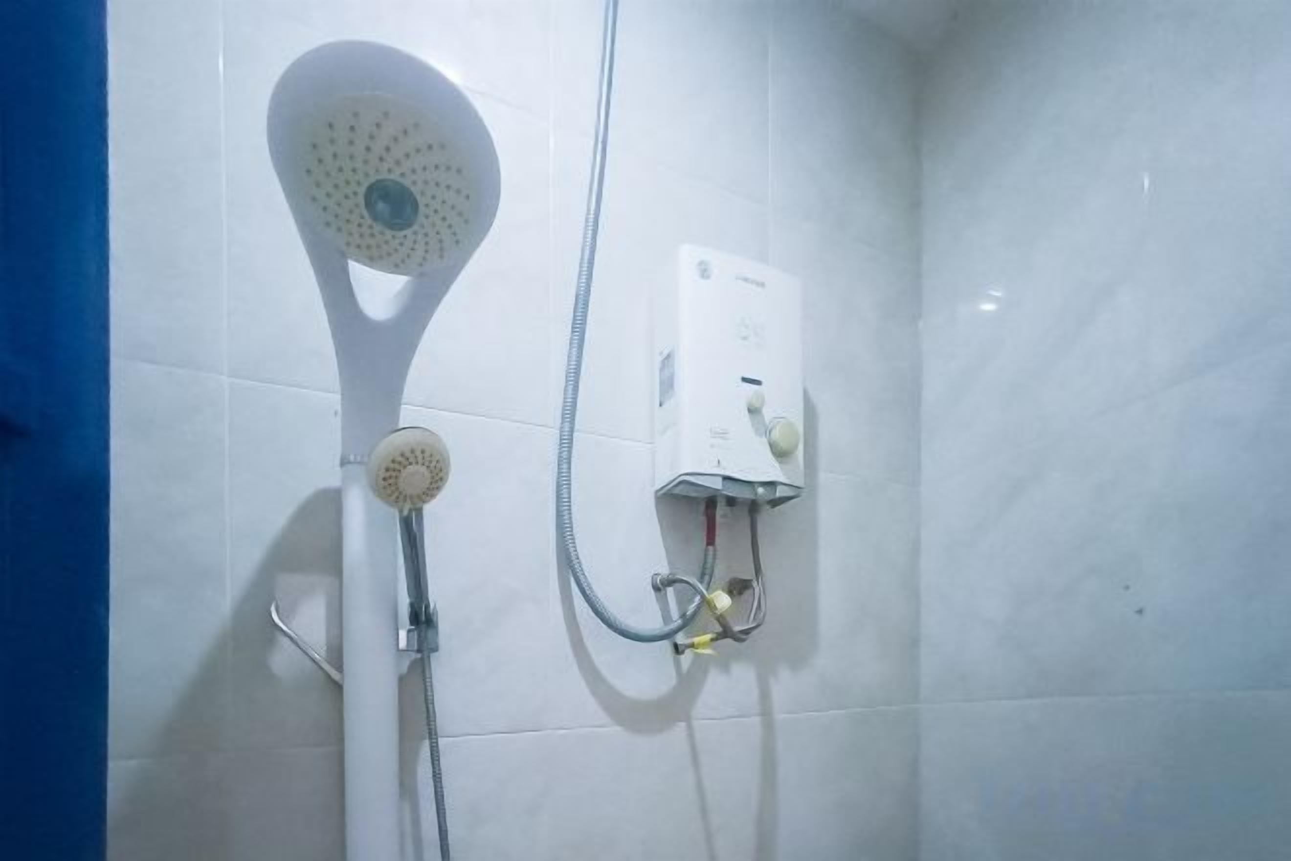Ένα ντους με ρυθμιζόμενη κεφαλή και ένα πάνελ ελέγχου τοποθετημένο στον τοίχο.