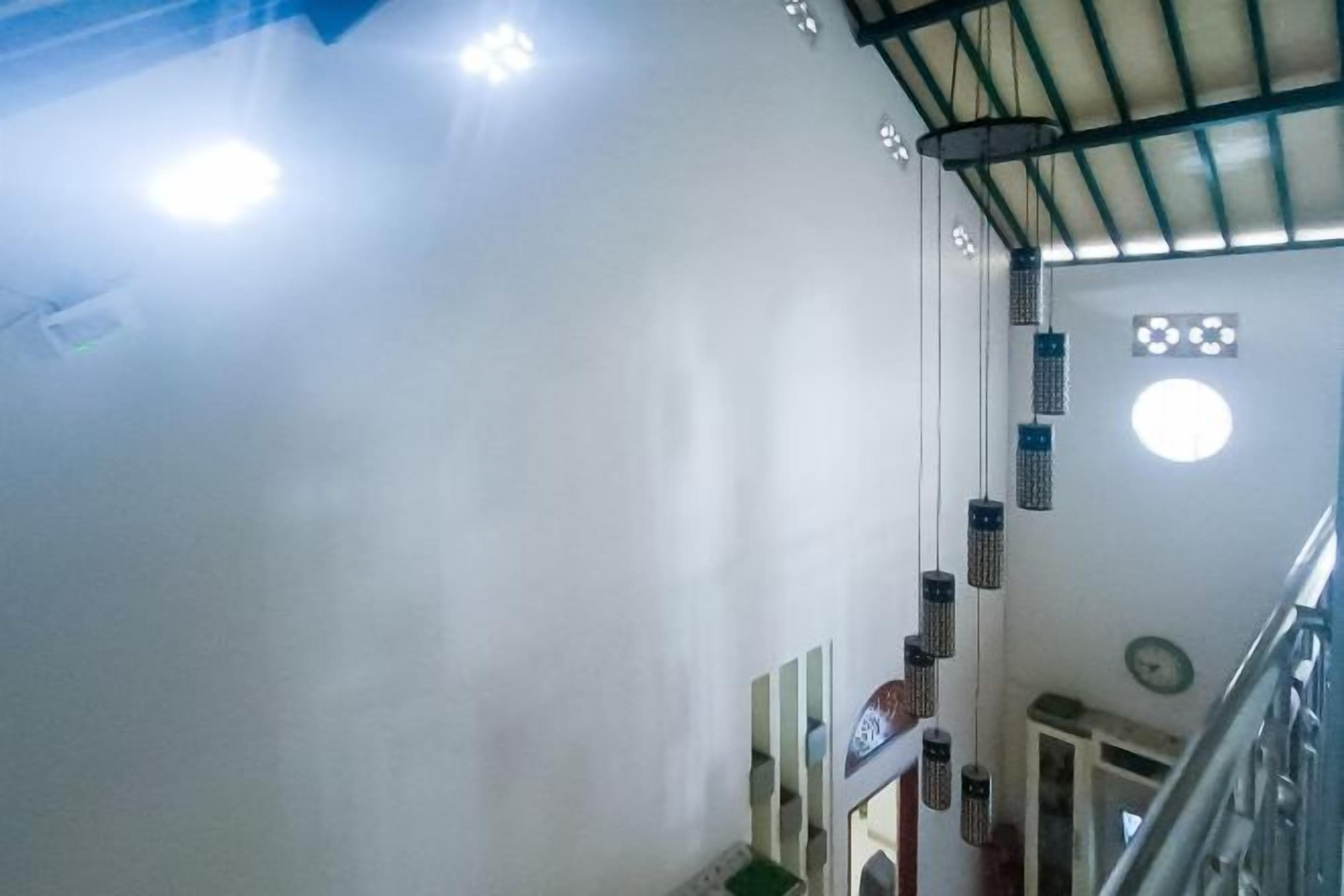 A staircase with a metal railing, a white wall, and hanging lights.