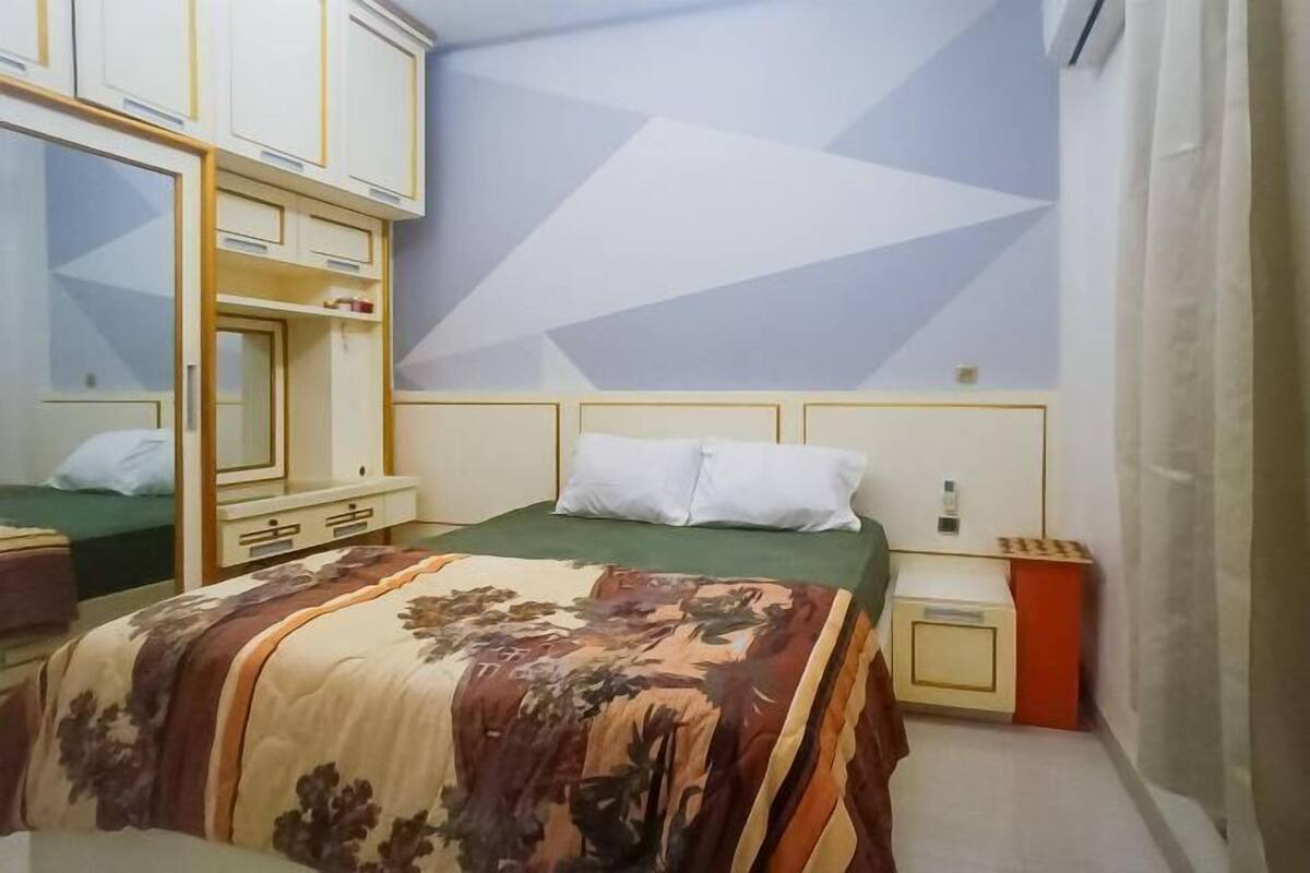A bedroom with a bed, a wardrobe, a nightstand, and a mirror.