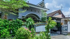 A residential building with a gated entrance, surrounded by lush greenery and a clear sky. - Vj Sweethome Syariah Near GOR Turida (Turida)