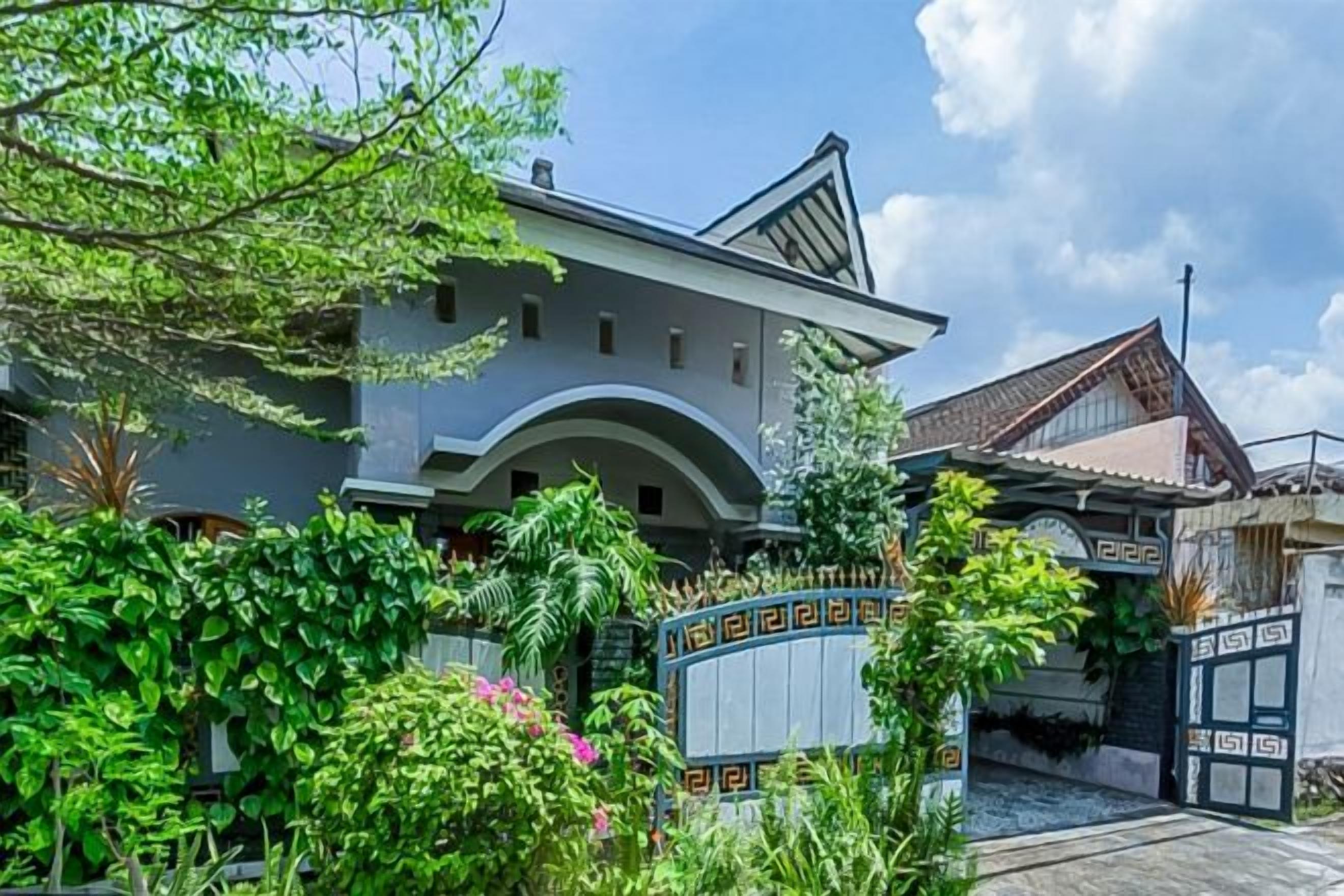 A two-story building with a gated entrance, surrounded by lush greenery.