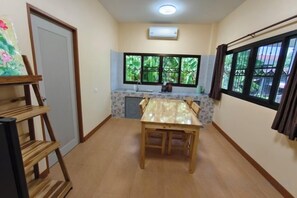 A compact kitchen with a dining table, a built-in oven, and a window with curtains. - Chiang Mai Downtown Privacy Home (Chiang Mai)