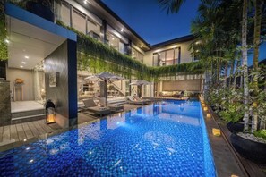 A modern pool area with a glass bottom, surrounded by a wooden deck and lounge chairs. - Villa Balimu Seminyak (Bali)
