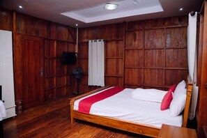 A bedroom with a wooden floor, a bed with white and red bedding, a ceiling fan, and wooden panel walls. - RedDoorz @ Villa Bukit Senyum Lombok (South Kuripan)