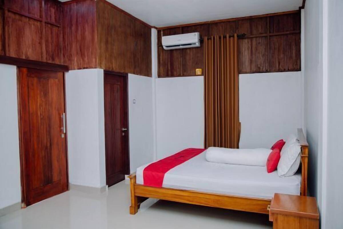 A bedroom with a wooden bed, white walls, and a wooden wardrobe.