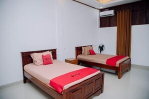A hotel room with two wooden beds, each with a red blanket and matching pillows. - RedDoorz @ Villa Bukit Senyum Lombok (South Kuripan)