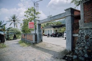 Une entrée fermée par un portail, avec une pancarte, une moto garée et un bâtiment en arrière-plan.