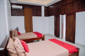 A hotel room with two beds, wooden paneling, and a ceiling fan. - RedDoorz @ Villa Bukit Senyum Lombok (South Kuripan)