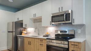 Eine moderne Küche mit Edelstahlgeräten, Holzschränken und einer gefliesten Spritzschutzwand.