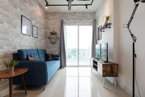 Una sala de estar moderna con un sofá, una mesa de centro, un mueble para televisión y un ventanal grande.