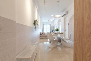 Un intérieur moderne avec un long couloir, un coin repas doté d’une table ronde et de chaises, et un espace détente avec un canapé.