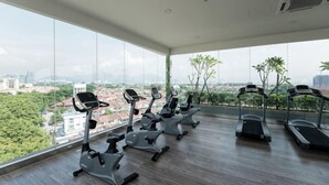 Ett gym med löpband och motionscyklar, stora fönster med utsikt över staden.