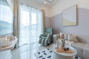 A modern living room with a sofa, a massage chair, a coffee table, and a large window with curtains. - SURIA NORTH KIARA BY FEEL HOME (Kuala Lumpur)
