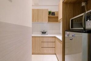 A compact kitchen with wooden cabinets, a microwave, and a refrigerator. - SURIA NORTH KIARA BY FEEL HOME (Kuala Lumpur)