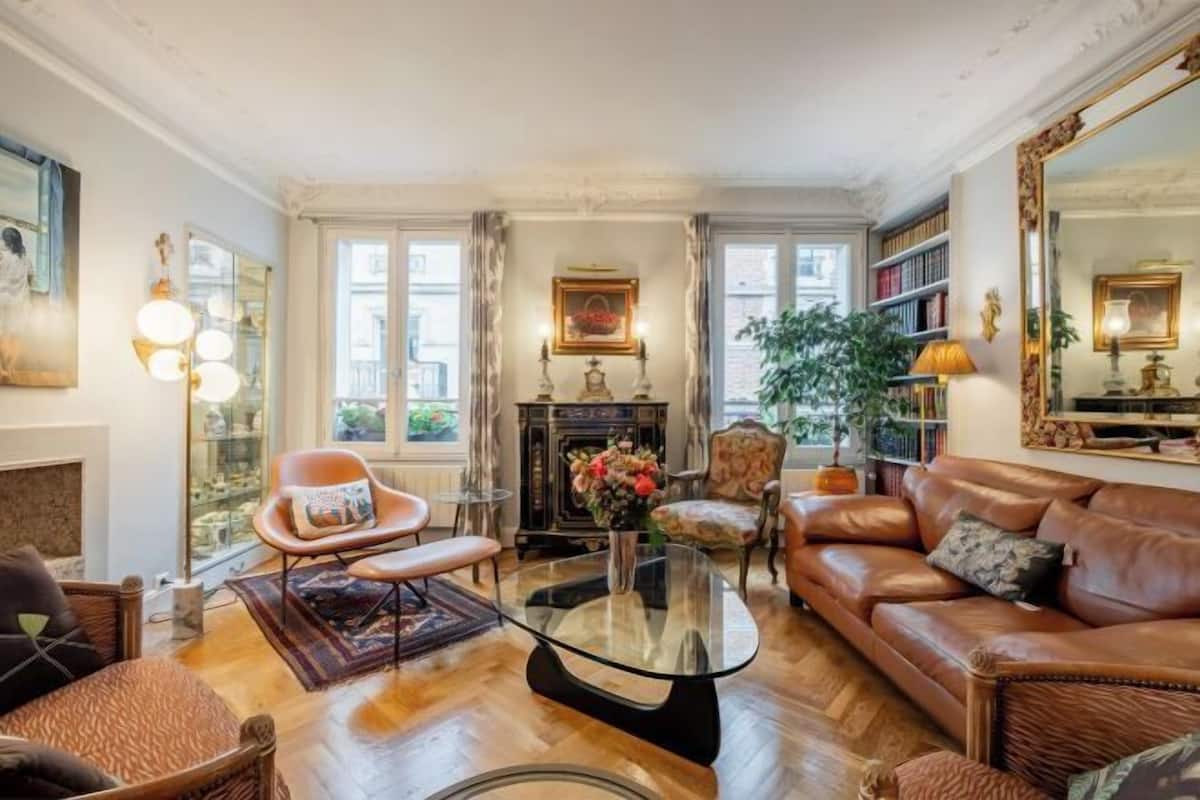 Un salon spacieux avec un canapé en cuir, une table basse en verre et une cheminée.