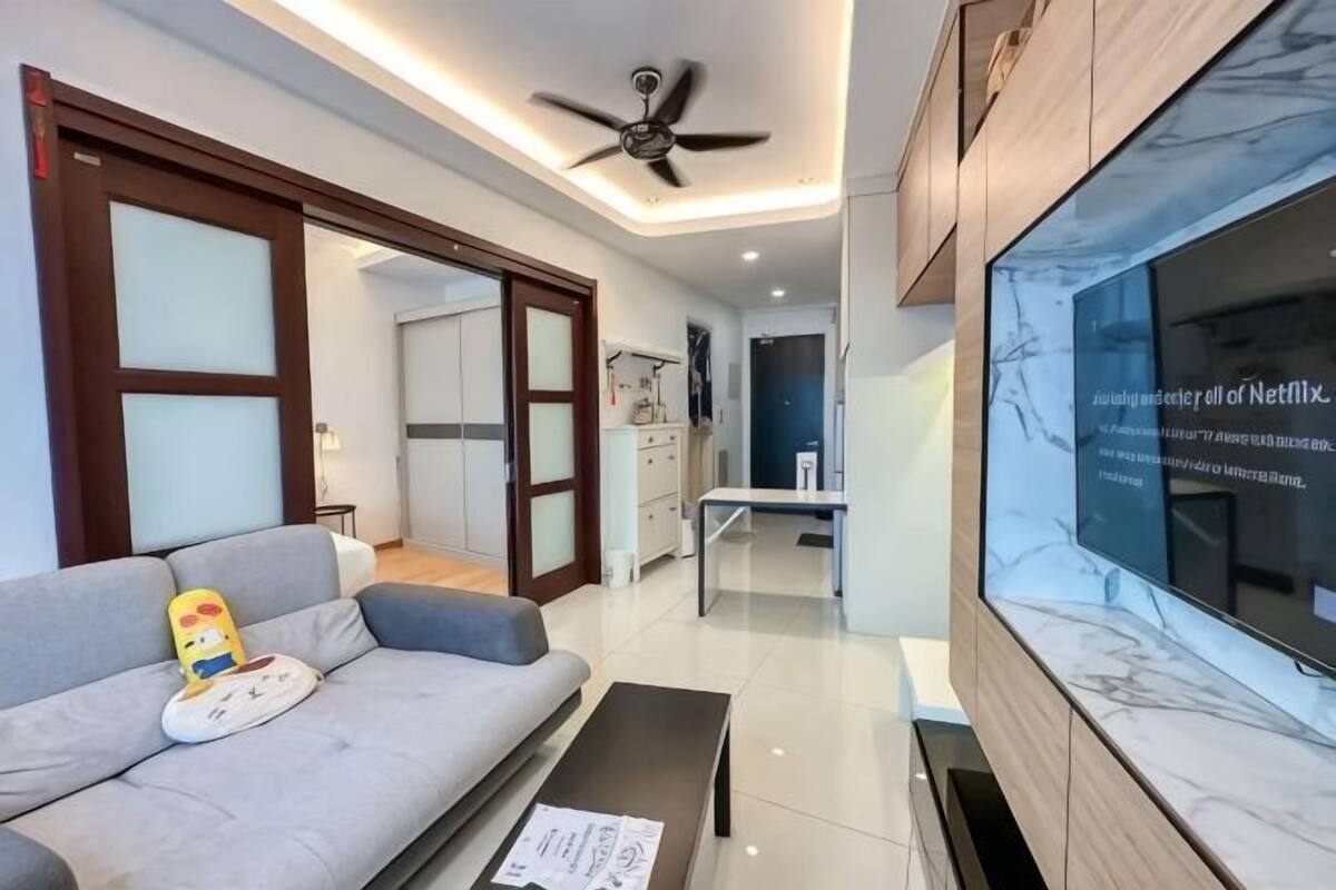 Uma sala de estar moderna com sofá, mesa de centro, ventilador de teto e uma janela grande com vista.