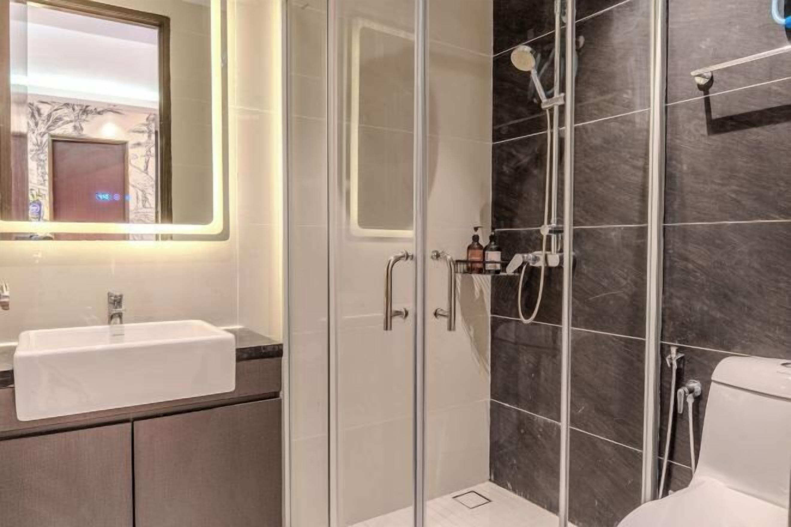A modern bathroom with a glass-enclosed shower, a white sink, and a large mirror.