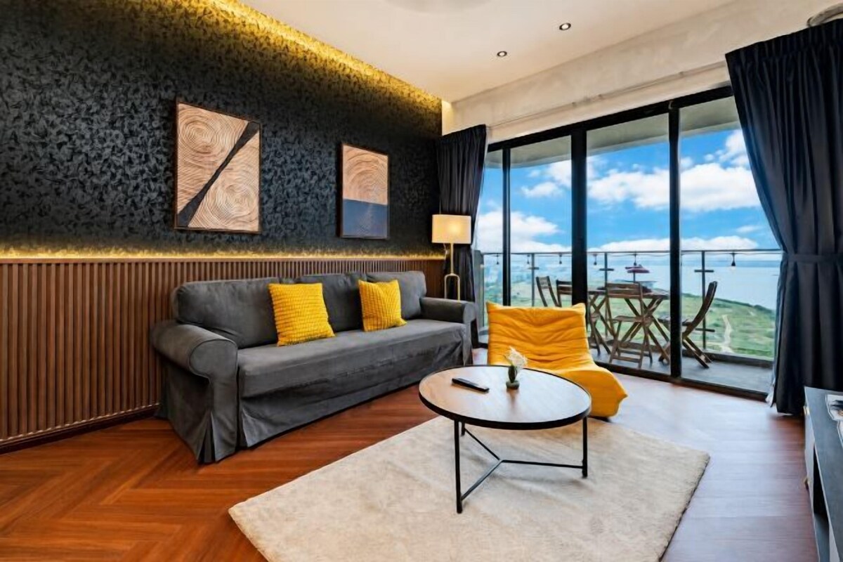 A modern living room with a sofa, a coffee table, and a view of the outdoors.