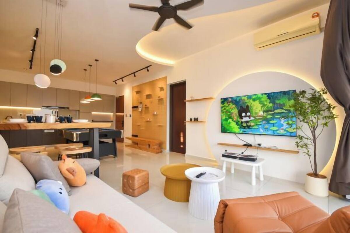 Uma sala de estar moderna com sofá, repouso para os pés e televisão de tela plana.
