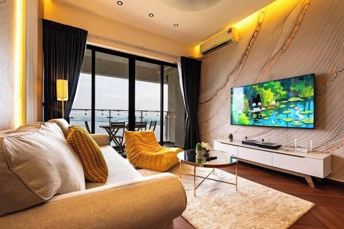 Uma sala de estar moderna com sofá, TV e vista para varanda.
