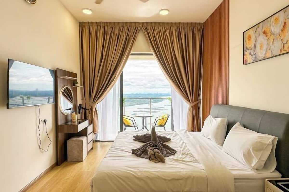Quarto de hotel com cama, televisão, escrivaninha com cadeira e varanda com mesa e cadeiras.