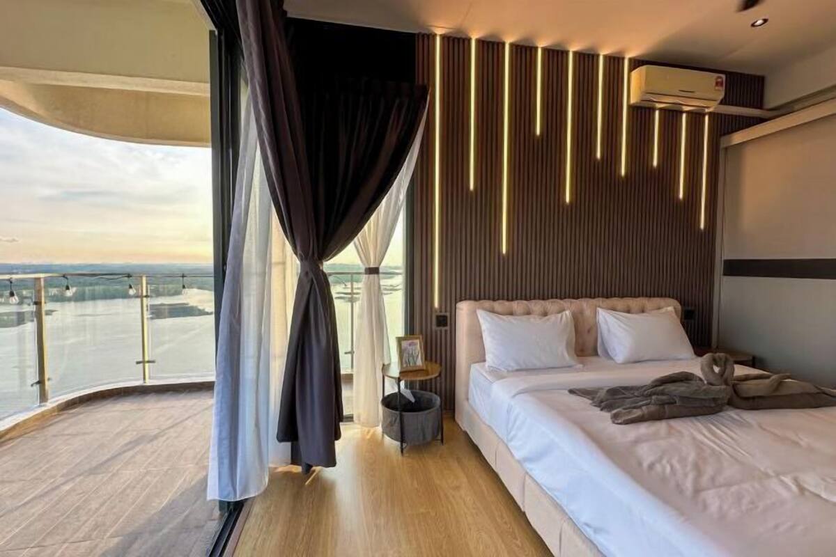 Quarto de hotel moderno com uma cama grande, vista da cidade e ar condicionado.
