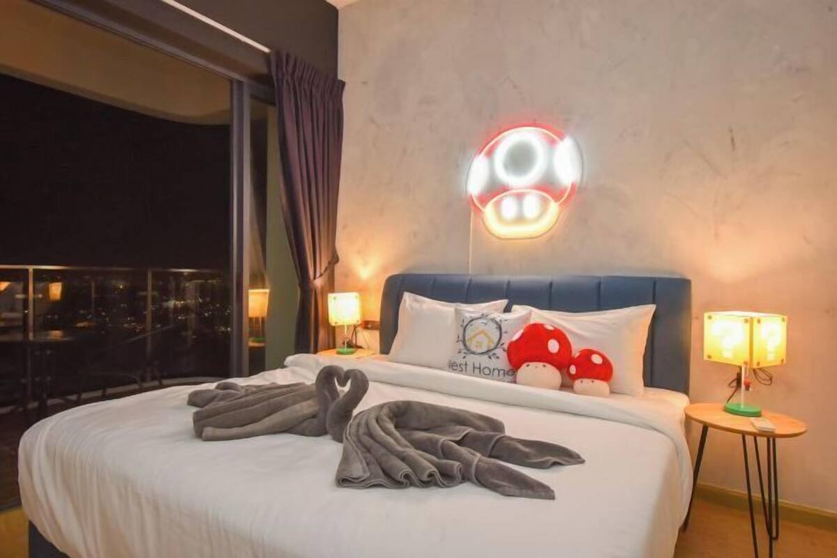 Quarto de hotel com cama, duas luminárias de cabeceira, luminária na parede e janela com cortinas.