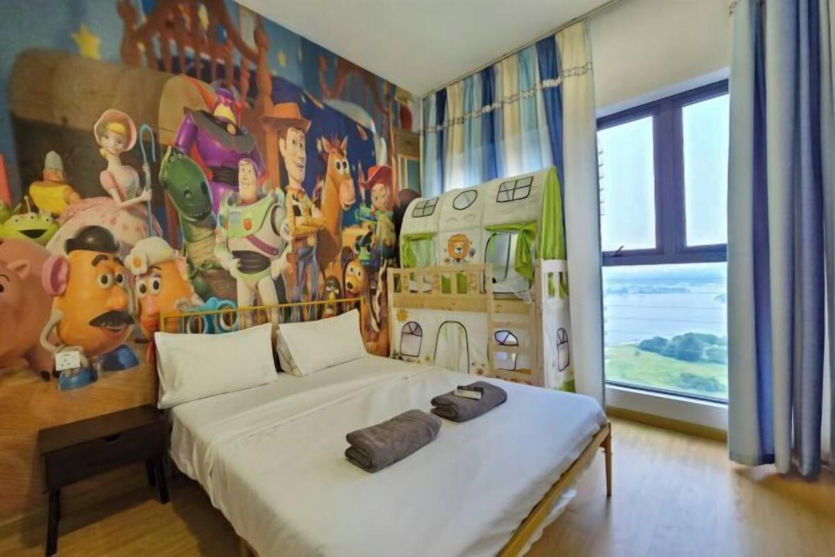 Quarto com cama, um mural na parede e vista para o mar através de uma janela.