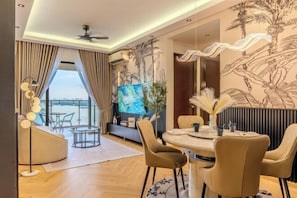 A modern dining area with a round table and chairs, a large painting on the wall, and a view of the outdoors.