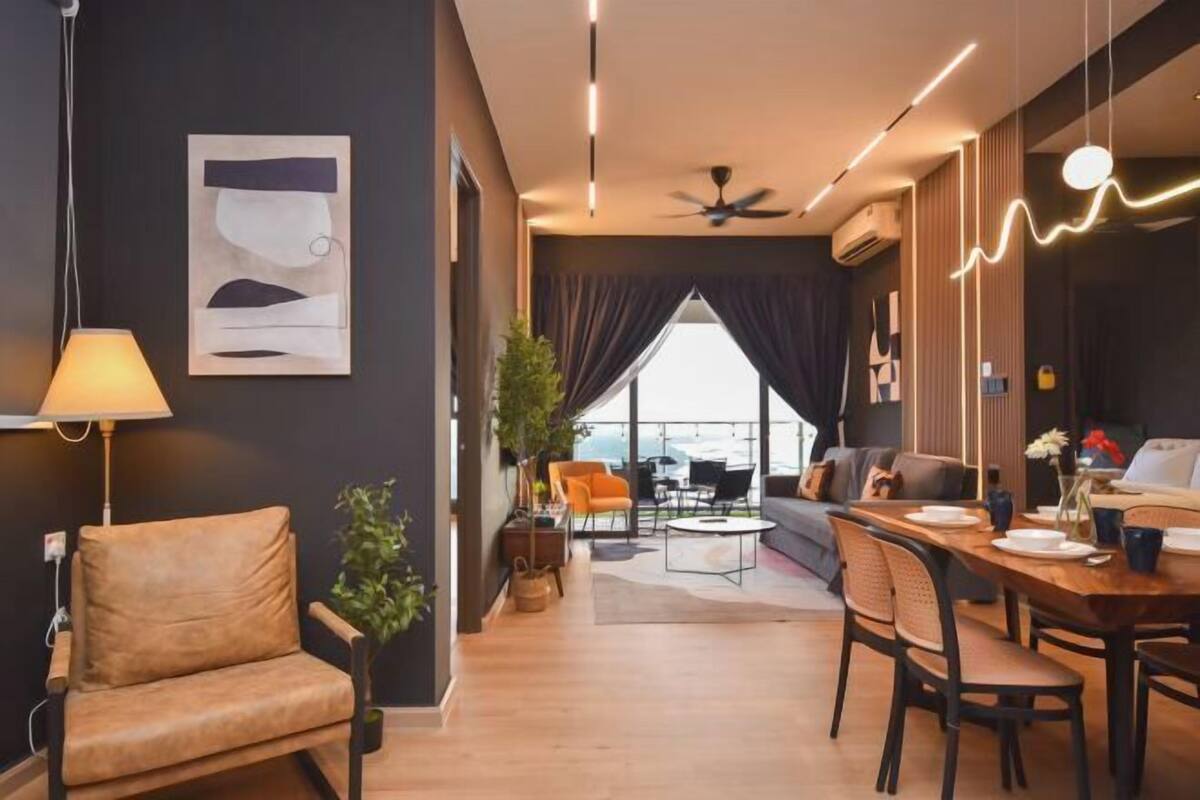 Uma sala de estar moderna com sofá, mesa de jantar e cadeiras, ventilador de teto e uma grande janela com cortinas.