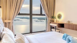 Una habitación de hotel con un ventanal grande, una cama, un escritorio con una silla y un espejo fijado a la pared.