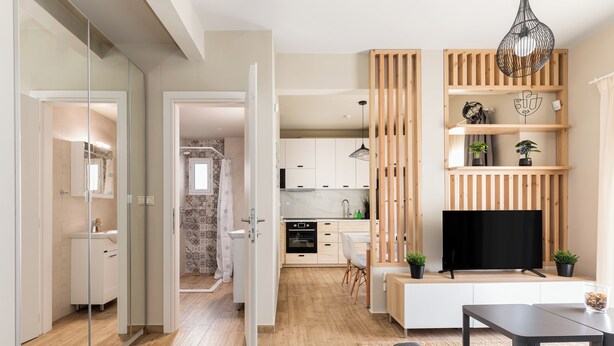 Un appartement moderne comprenant une cuisine, un coin repas et un salon. On y trouve une télévision, un canapé et une table à manger.