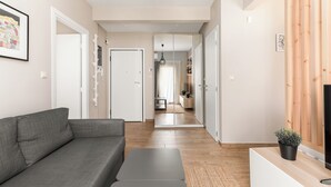 Un salon moderne avec un canapé gris, une petite table basse et un meuble TV en bois.