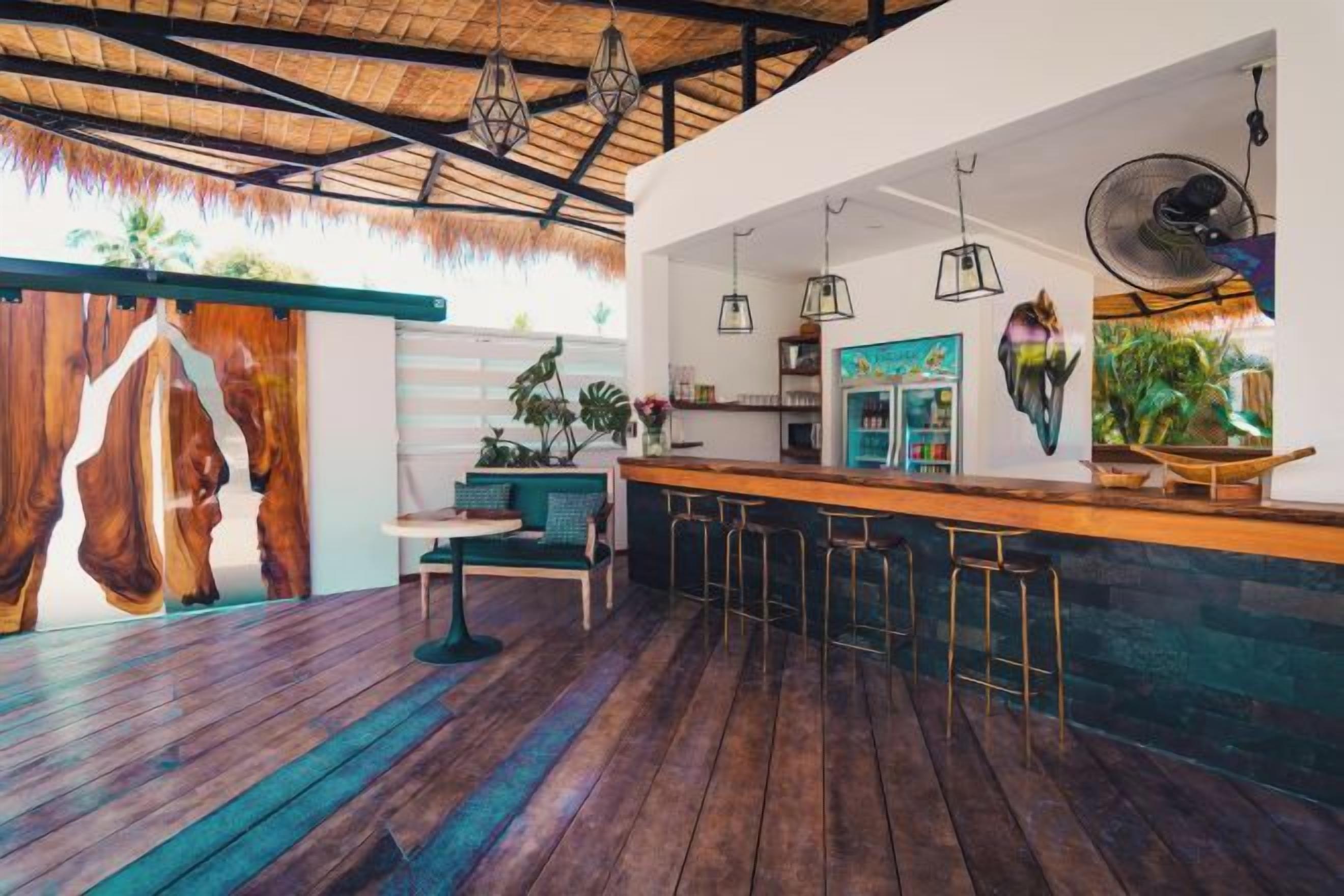A modern kitchen with a bar area, wooden flooring, and hanging pendant lights.