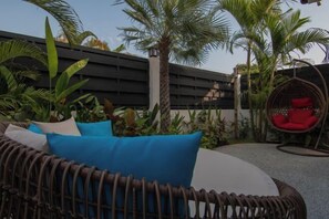 A wicker sofa with blue cushions, a hanging chair with red cushions, and a variety of tropical plants. - La Belle Vie - Boutique Hotel Adults Only (Koh Phangan)