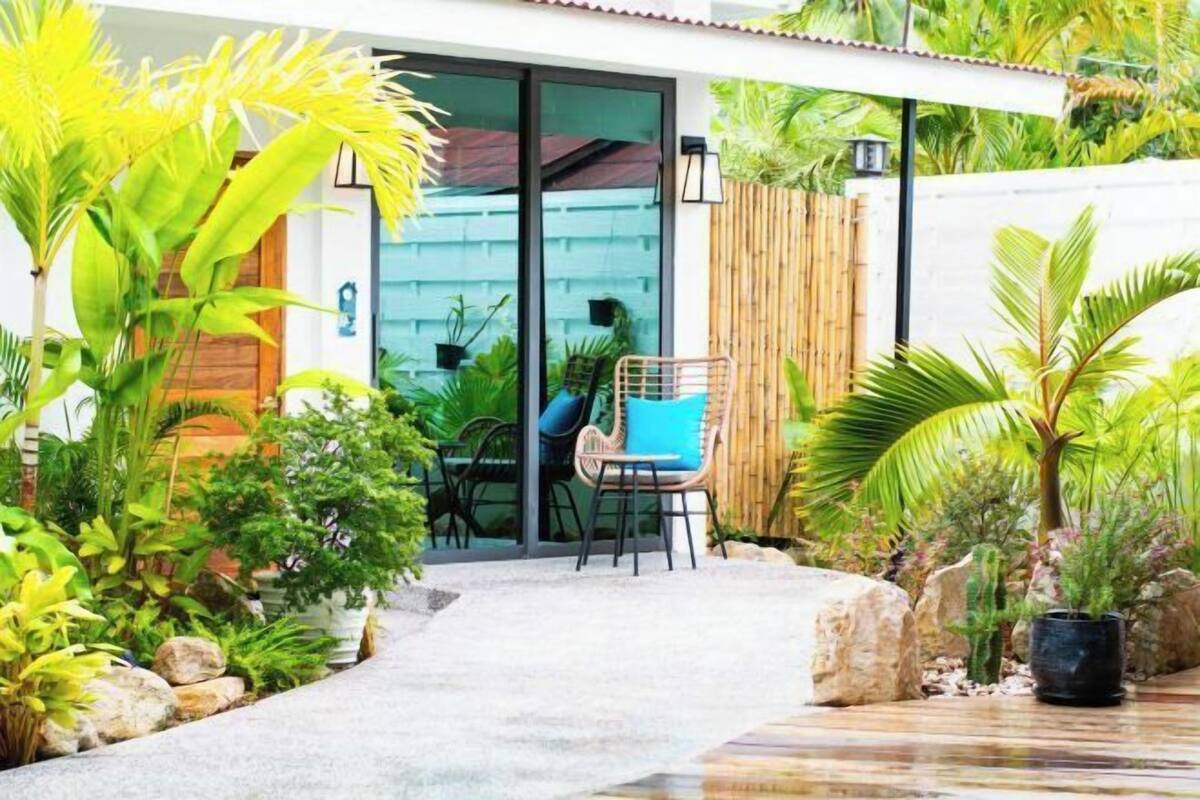 Eine Terrassenfläche mit Sitzgelegenheiten, umgeben von üppiger Bepflanzung und einem Holzzaun.