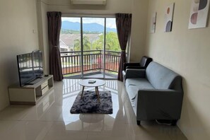 A living room with a sofa, a TV, a coffee table, and a balcony with curtains. - Apartment Klebang ipoh Near Aeon,Mcd,Free packing (Ipoh)