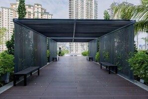 Een overdekt buitengebied met banken en potplanten, omringd door hoge gebouwen.