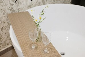 A bathtub with a wooden tray holding two glasses and a vase with flowers. - THE PANO BY FEEL HOME (Kuala Lumpur)